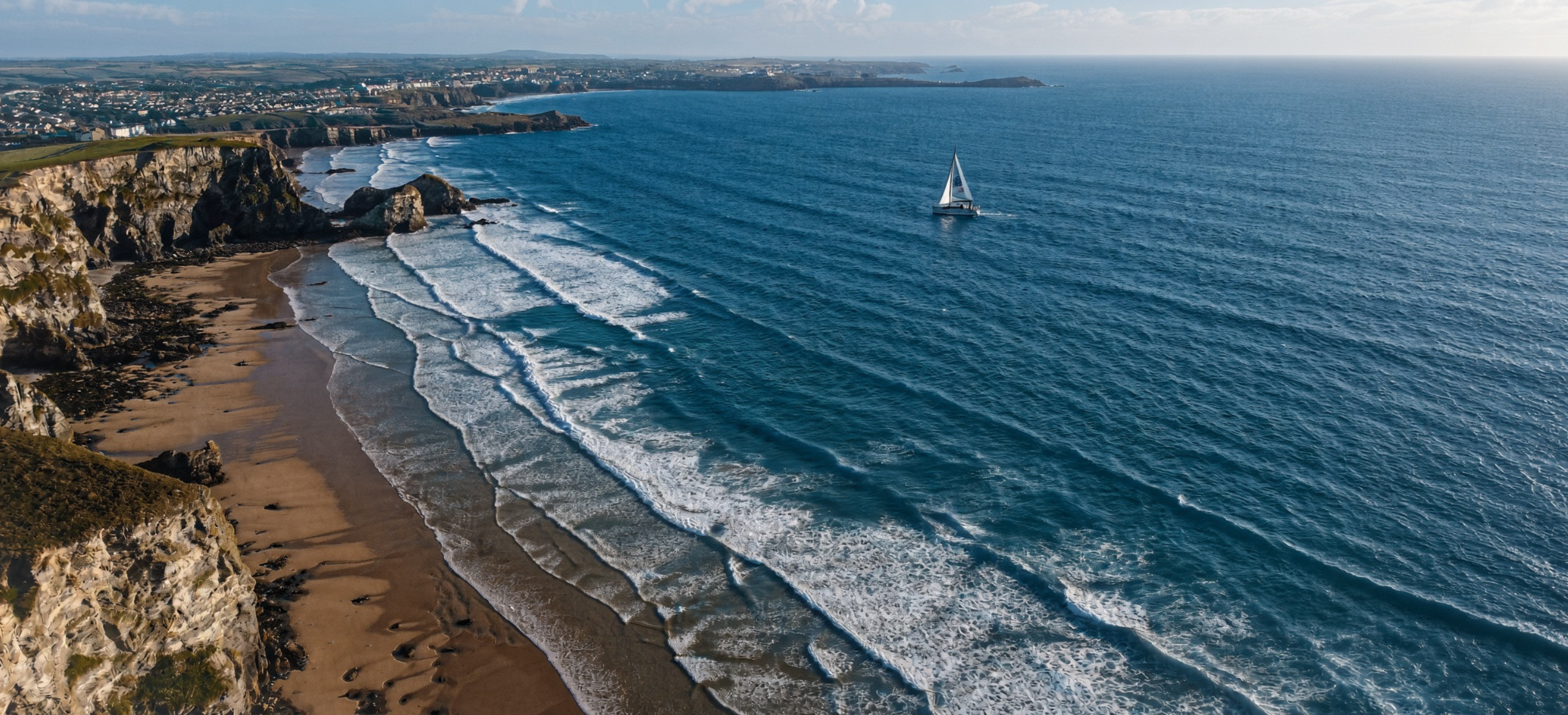 Aerial view of the Cornish coast near Newquay with a sailing boat